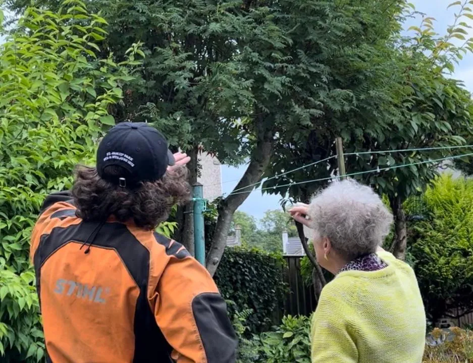 Gio, owner of Oasis Tree & Garden Care, talking with a customer in their garden.