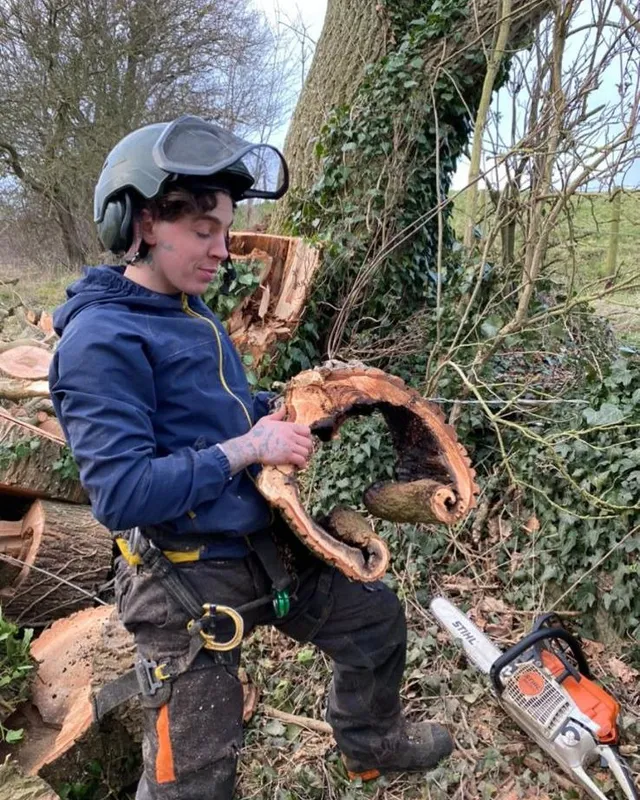 Gio holding a section of a dangerous, hollow tree that he safely dismantled.